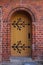 Wooden plank street door with forged metal parts. Beautiful door with flower ornament. Rounded doorway