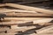 Wooden planks, rods and poles, stockes in piles and stacks, waiting to be used as lumber by a carpenter on a construction site.
