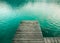 Wooden platform as bridge pier deck on an alpine lake with beautiful green turquoise clear water