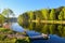 Wooden platform and calm water of the lake. The spring forest and the blue sky are reflected in the water.