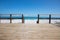 Wooden platform with rails and wooden stairs leading to a white sandy beach and turquoise waters of the ocean