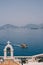 Wooden pleasure yacht sails against the background of the city of Budva. Bell tower of the church on the island of Sveti