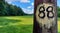 Wooden pole marked with a number 88 on a blurred background of a meadow