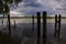 Wooden poles of a mooring in the water with their reflections casted in the water of a river in the italian countryside