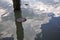 Wooden poles of a mooring in the water with their reflections casted in the water of a river in the italian countryside