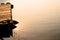 Wooden pontoon surrounded with lifebuoy floating on ripple water surface with reflection of sun light during sunrise.