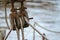 Wooden pulley block with weathered ropes on an historic sailing boat against the blurry sea water