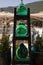 A wooden rack with three large glass bottles full of green liquid outside of a craft shop in the KIONI port, ITHACA