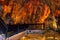 Wooden railing of a staircase against the background of orange-yellow fiery stone formations underground in Damlatas cave Alanya