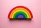 Wooden rainbow toy on a pink background