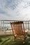 A wooden reclining chair with small tree on side table with Stainless steel balcony railing overlooking city view