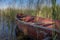 Wooden red rowboat moored to a rustic jetty