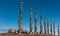 Wooden ritual pillars stand in a row against the blue sky.