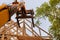 A wooden roof truss being lifted by a boom truck forklift in the roof a new home