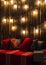 Wooden room in rustic house with wall and designer light bulbs, decorated place for seat. Red gray pillows.