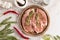 a wooden round tray with two juicy mouth-watering raw pork neck steaks for baking. marble background. top view.