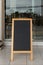 Wooden rustic blackboard in front of restaurant entrance. Mock up Menu Blank Blackboard sign stand Shop Cafe Restaurant. Street Ma