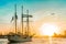 Wooden sailboat sailing toward dramatic sunset beginning new travel adventure with flying bird