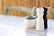 Wooden salt and pepper grinders on traditional Greek tavern outdoor table in afternoon soft light. Ashtray - wooden chairs.