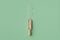 Wooden scoop of homeopathic granules on green background. Homeopathy medicine. Top view.