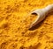 Wooden scoop with yellow turmeric powder closeup