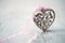 Wooden sculpted heart with pink lace ribbon in romantic setting on white grey wooden underground and soft bokeh