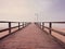 Wooden sea pier at misty morning with light posts. Heavy mist