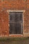 A wooden seasoned barn door in a brick wall of a out building on a farm