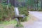 A wooden seat along a Scottish mountain forest trail with pines trees and green vegetations