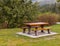 Wooden seat in a park. Picnic in the park. Rest in the open area. Wooden picnic table and seats