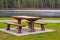 Wooden seat in a park. Picnic in the park. Rest in the open area. Wooden picnic table and seats by the river or lake