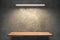 Wooden shelf on concrete wall mockup under light front perspective view, blank for design