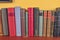 Wooden shelf with historic,decorated, vintage books. Old books on yellow and claret background