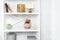 Wooden shelving unit with decor near grey wall. Bookcase with photo frame mockup and candles, living room interior details