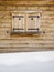 Wooden shutters on a cabin window with snowdrift in foreground