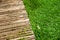 Wooden sidewalk and green lawn for background or texture.