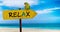 Wooden sign on beautiful beach and clear sea wit text relax. A green parrot sits on a pointer to a tropical paradise