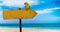 Wooden sign with empty place for your text on a beautiful beach and clear sea . A green parrot sits on a pointer to a tropical