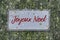 Wooden sign on fir branches with joyeux noel