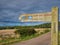 A wooden sign post points the way of the Coast and Castles cycle route and Northumberland Coast Path.