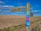 A wooden sign post points the way of UK National Cycle Route 1 and the Coast and Castles route in Northumberland, UK