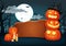 Wooden signboard with candles and glowing halloween pumpkins with witch hat.