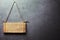 Wooden signboard hanging on rope on gray textured wall