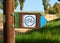 Wooden signpost with a bicycle symbol indicating the moving direction for cyclists along a trail in summer green nature park