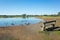 Wooden sitting bench and some wild birds at Presidents Park Lake. Background texture of a public park with a lake and green field