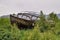 Wooden skeleton of old boat in low forest. Wooden boat frame, grass and small trees around. Abandoned ship wreck in the forest.