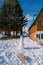 Wooden sleds stand near a snowman near a wooden cottage in the yard