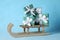 Wooden sleigh with Christmas gift boxes on light blue background