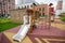 A wooden slide with a gazebo on the playground in kindergarten against the background of houses