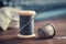 Wooden spool of blue thread, thimble and including pins on table. Blue fabrics for sewing and measuring tape on background